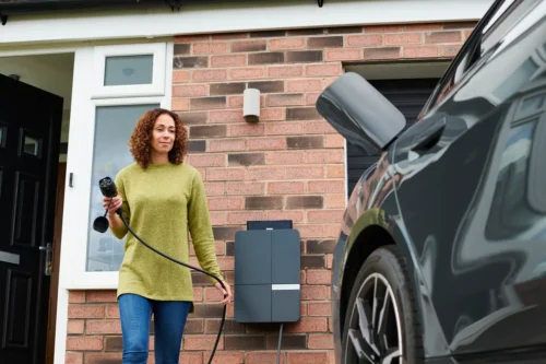 Woman holding an EV charger plug with the car port open