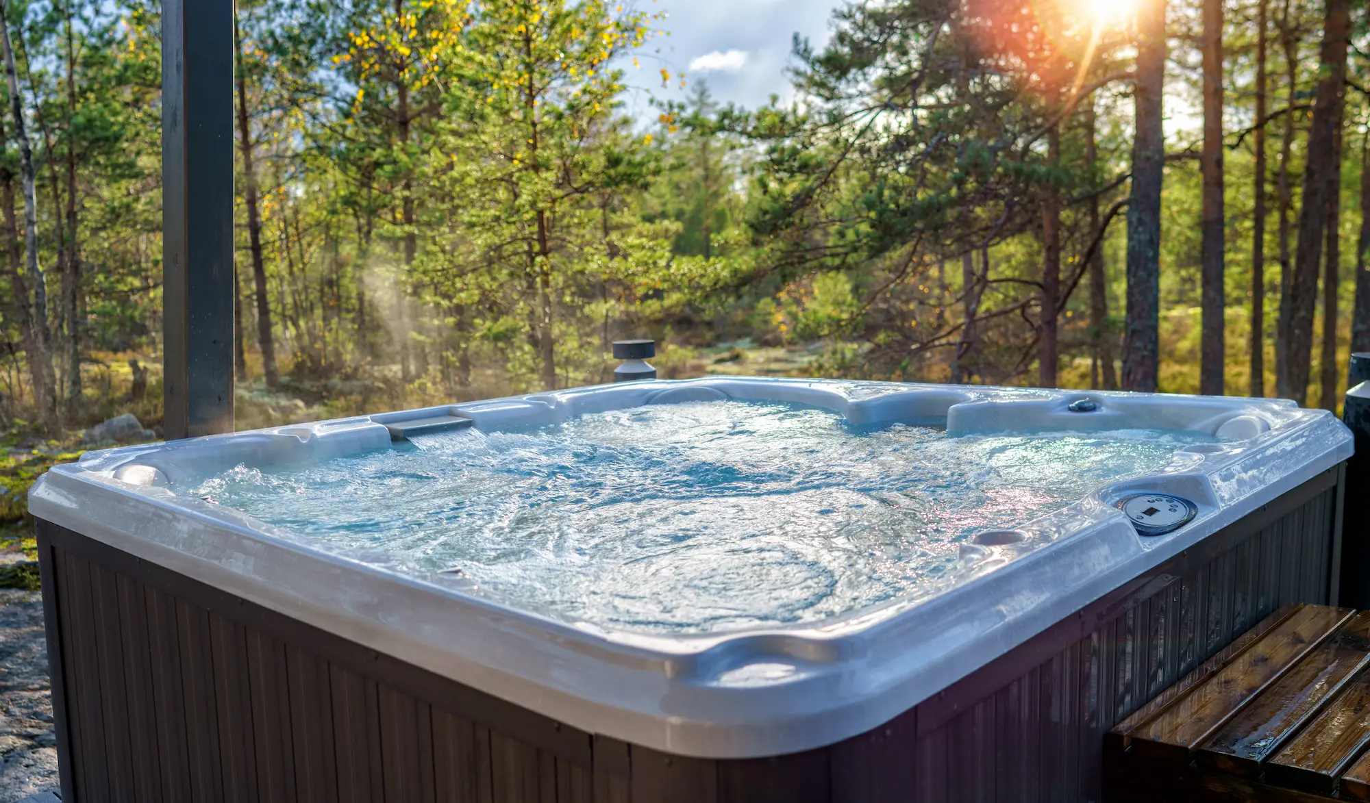 Outdoor hot tub against a forest, tree-filled background
